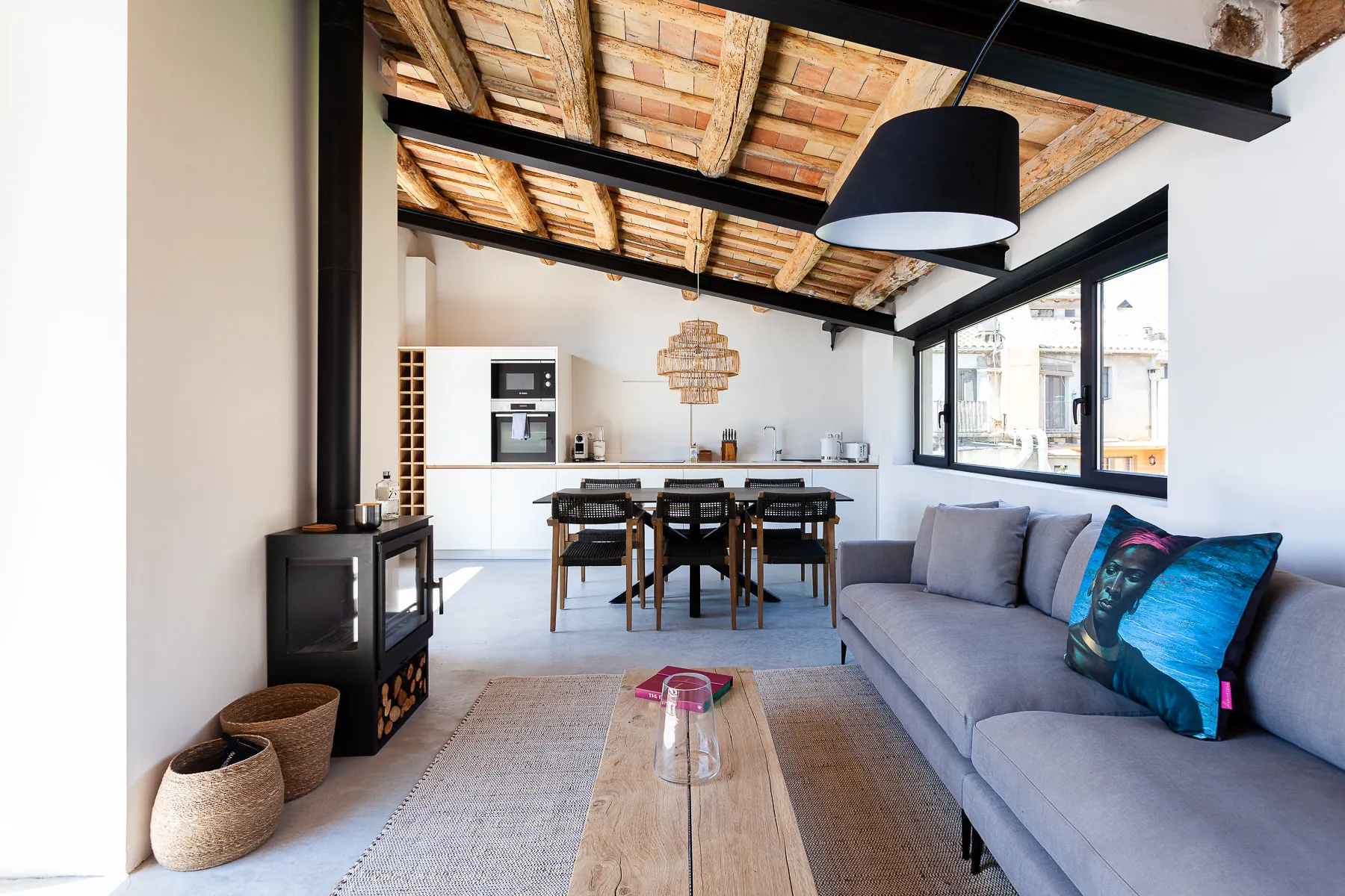 The top-floor living room, with exposed timber beams and a wood-burning stove