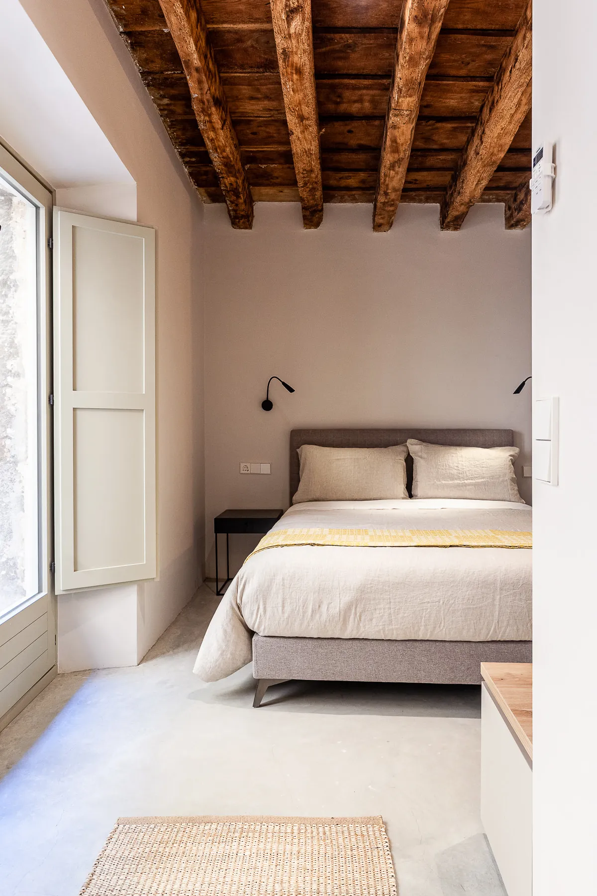 Bedroom with a queen bed, linen bedding and a reading light