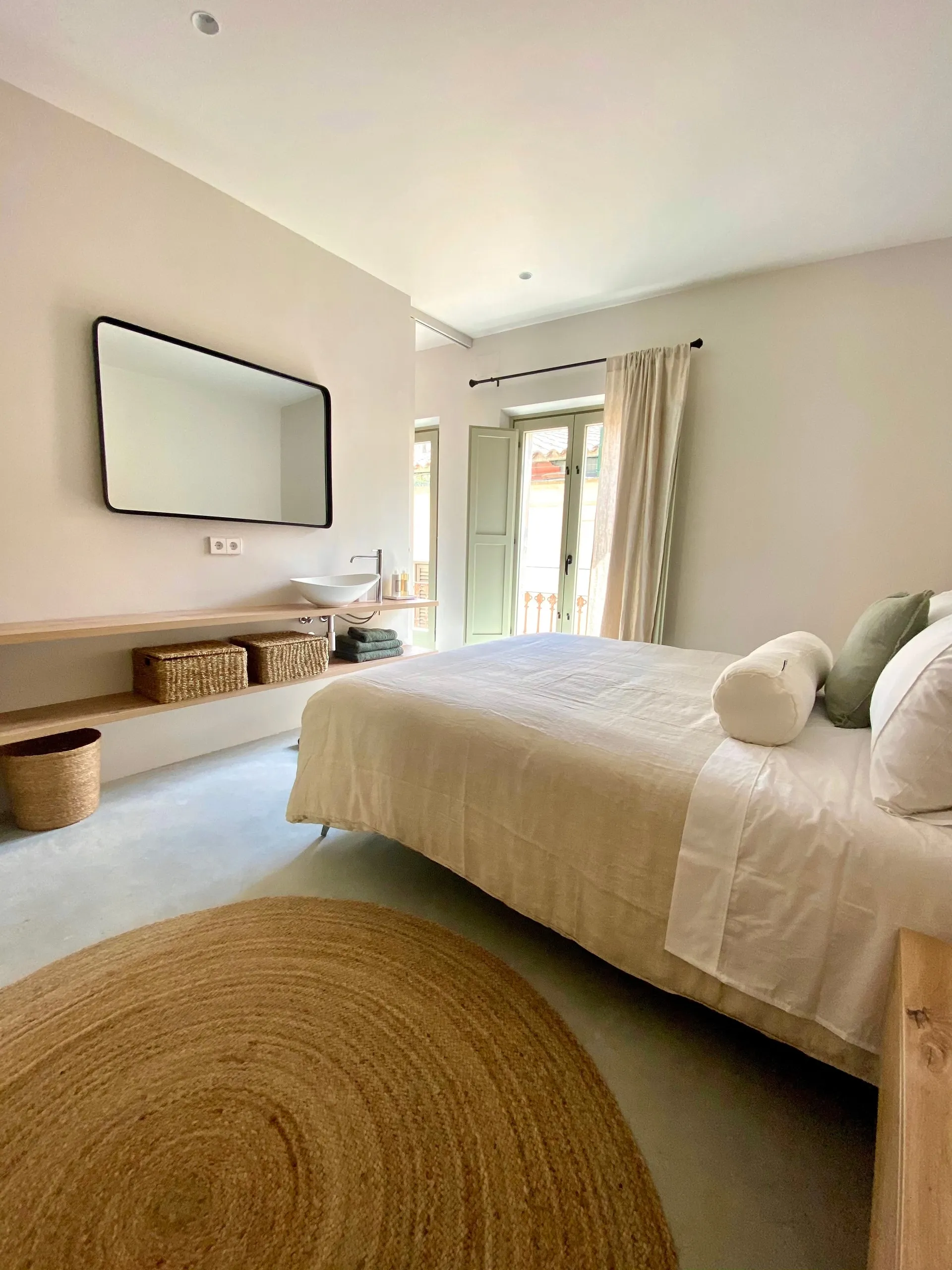 Bedroom with a queen bed, large mirror and window onto the street