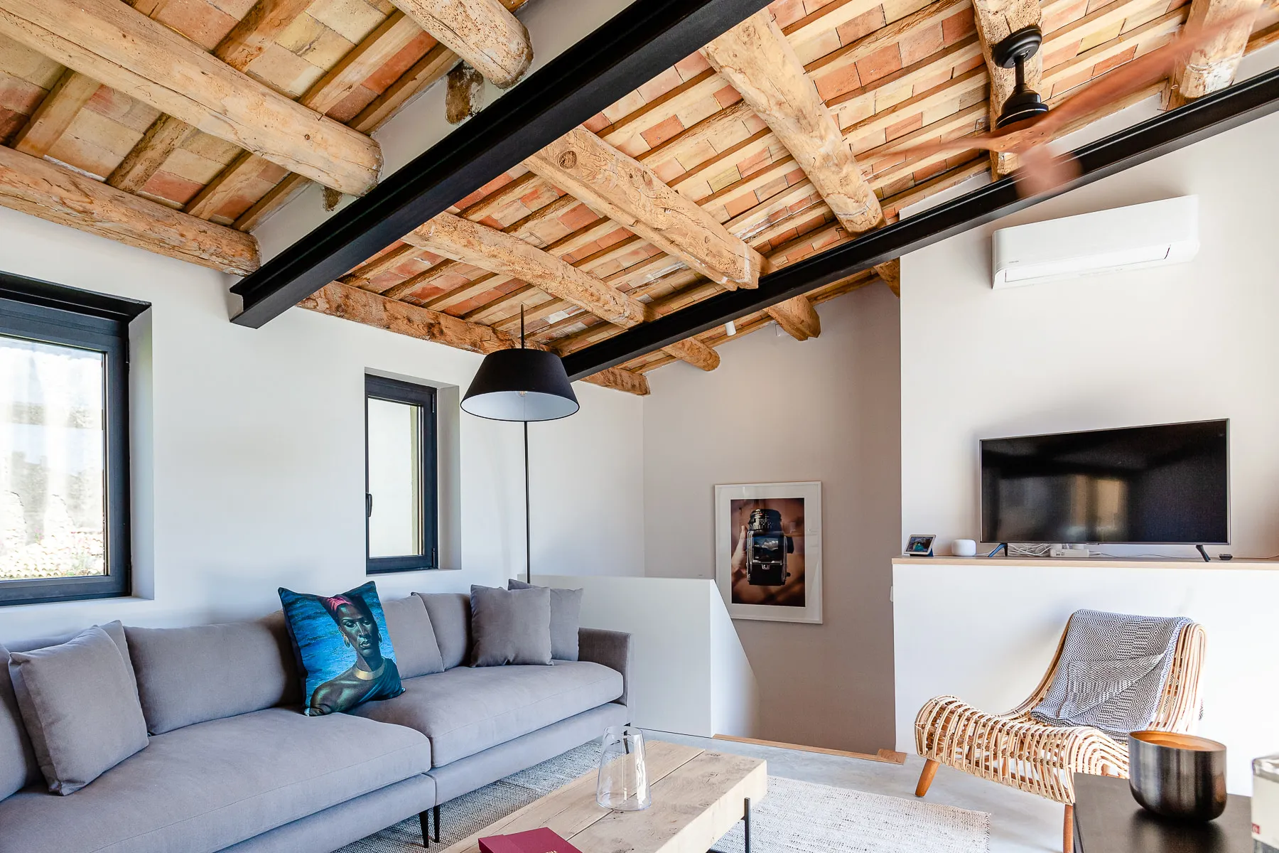 Top-floor living room with a grey sofa, exposed beams and a wood-burning stove